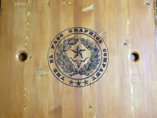 El Paso Graphics Company logo engraved into wood with black color fill
